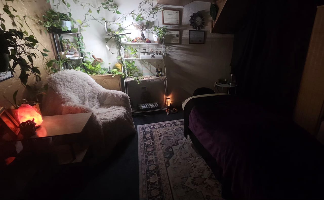 The Soluna Touch Therapy treatment room with houseplants, a glowing salt lamp, and a massage table